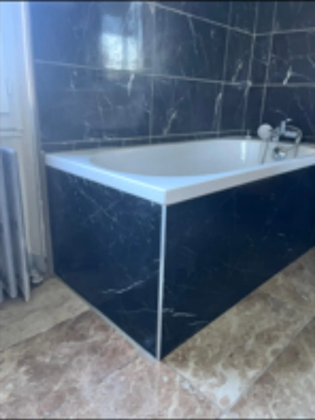 Baignoire habillée d'un tablier en marbre noir assorti aux murs par Bony Plomberie