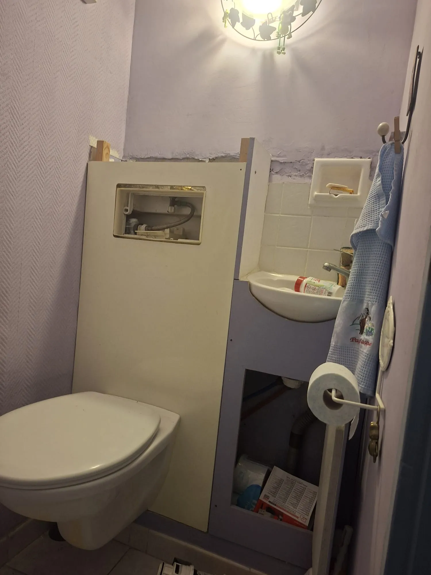 WC suspendu à l'habillage ouvert, mécanisme apparent et mur abîmé, avant l'intervention de Bony Plomberie